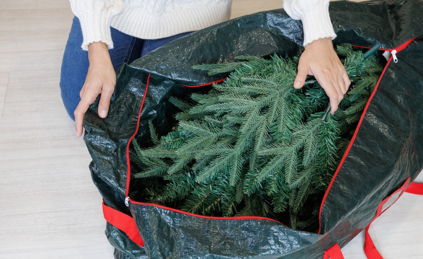 Woman taking an artificial Christmas tree out of a storage bag.
