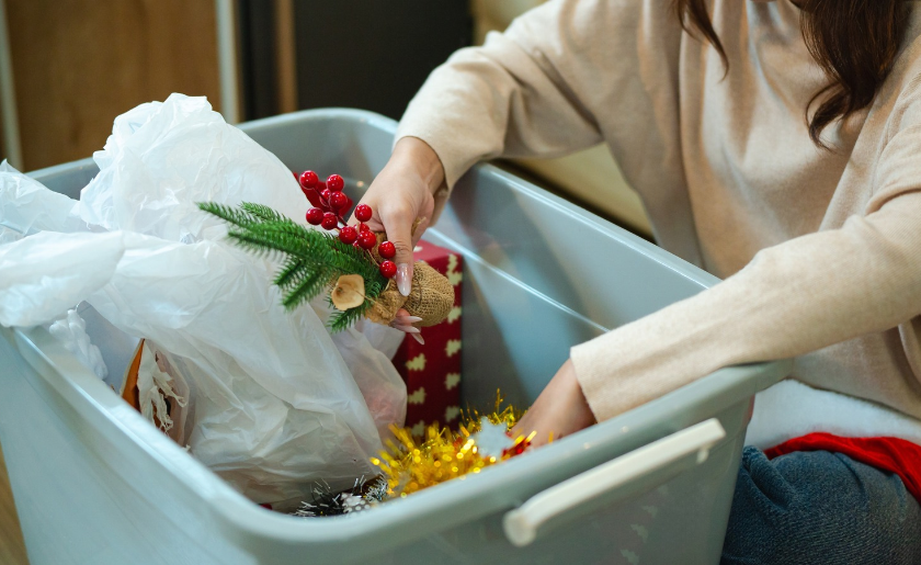 Woman putting away Christmas decorations in storage bins.